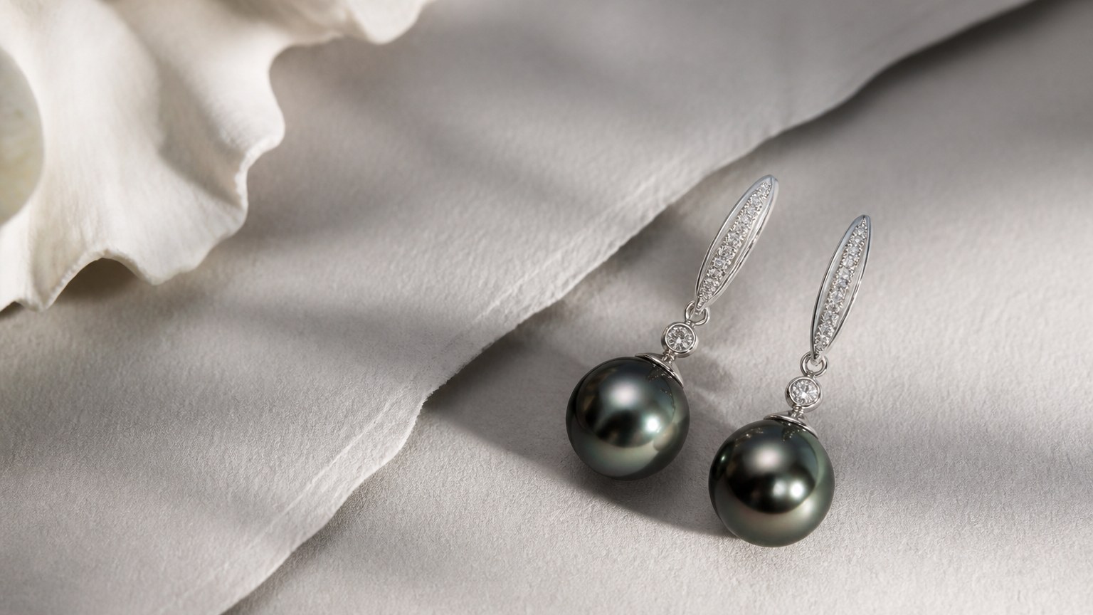 Paire de boucles d'oreilles pendantes avec perles de culture noire de Tahiti sur papier gris